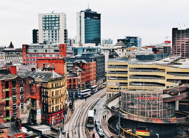 Aerial view across Manchester's rooftops, mixing red brick and glass towers