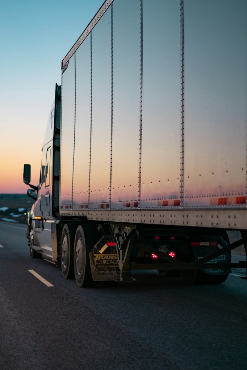 Rear of a freight vehicle on the road at dusk, sky fading over the carriageway