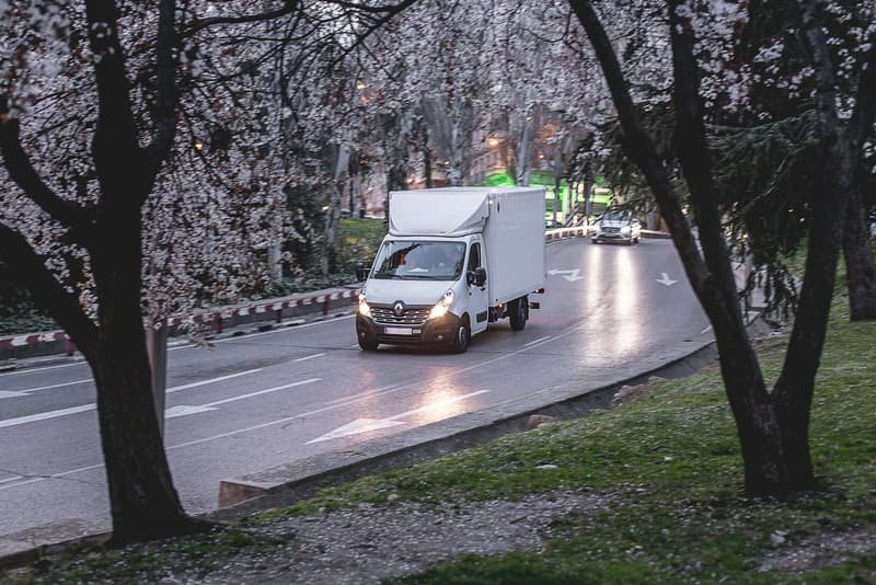 Courier van on the road at dusk with lights on