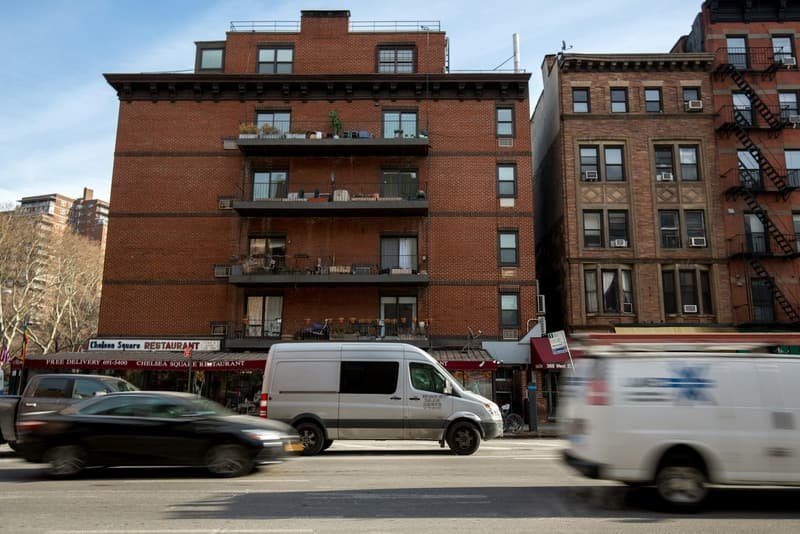 White van passing a brick building, background streaked with motion